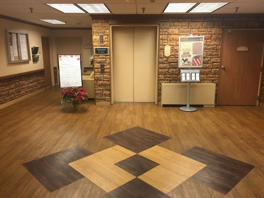 Lobby area with an elevator, informational board, and decorative flooring