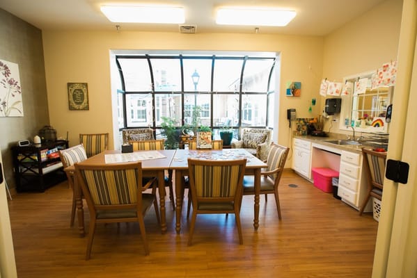 Spacious dining area with a large table and chairs in a senior living facility