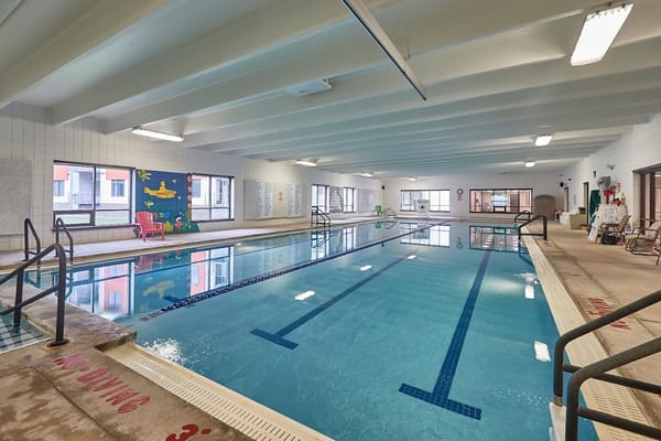 Indoor swimming pool at TimberCrest, featuring a colorful mural and chairs.
