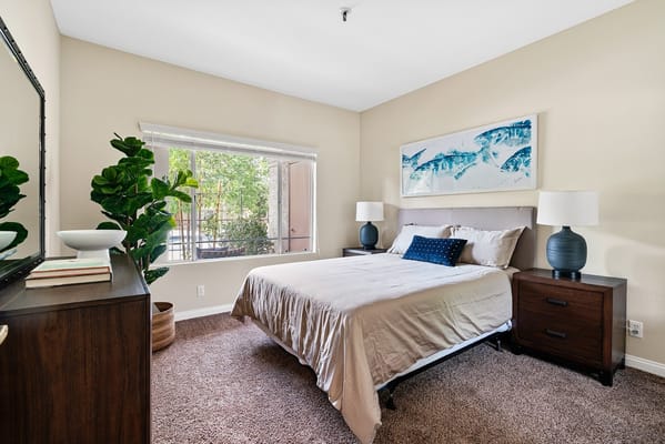 A well-decorated bedroom with a bed, nightstands, and window view.