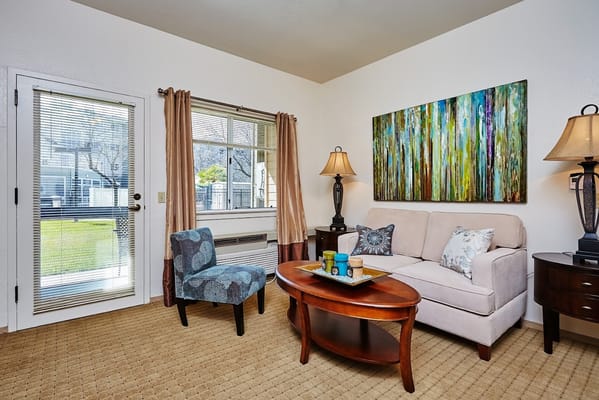A cozy living room featuring a sofa, patterned chair, and colorful artwork