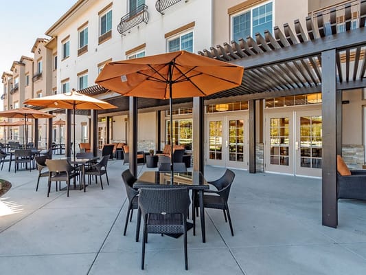 Outdoor seating with orange umbrellas at Westmont of La Mesa