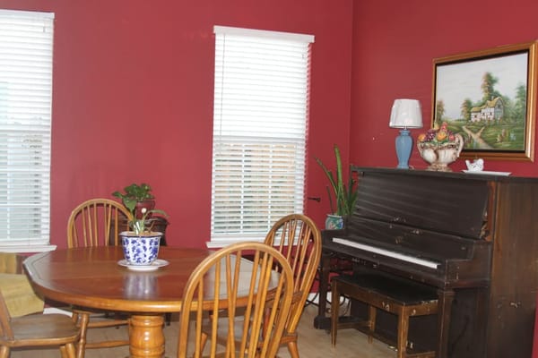 Living room featuring a round dining table, chairs, and a piano against red walls