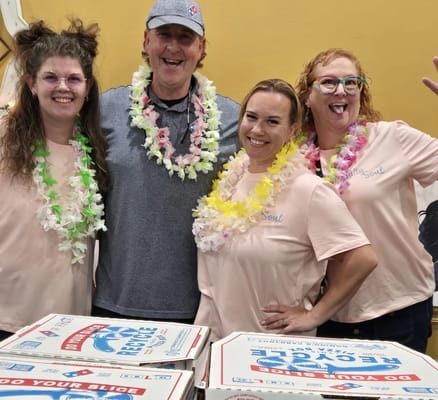 Staff and residents enjoying pizza party with leis