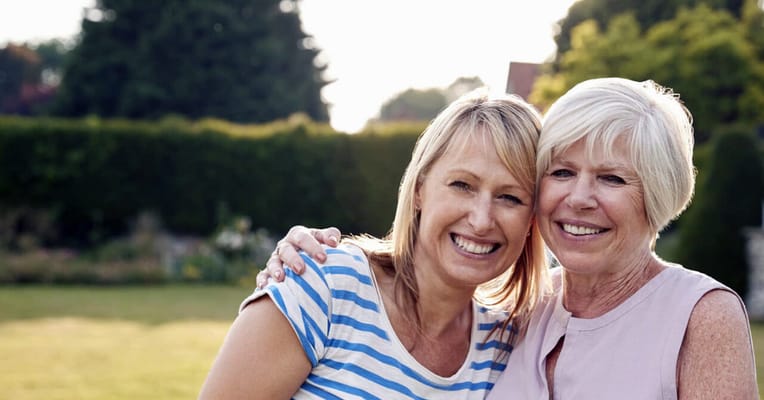 Two women smiling together in a garden
