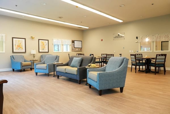 Bright common area with chairs and tables for residents