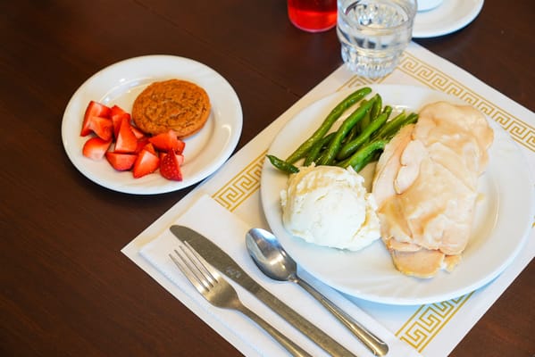 Plate of turkey, mashed potatoes, green beans, strawberries, and a cookie