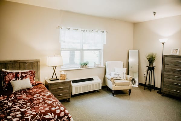 Cozy resident room featuring a floral bedspread and armchair