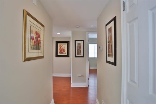 Hallway with framed artwork and wooden flooring