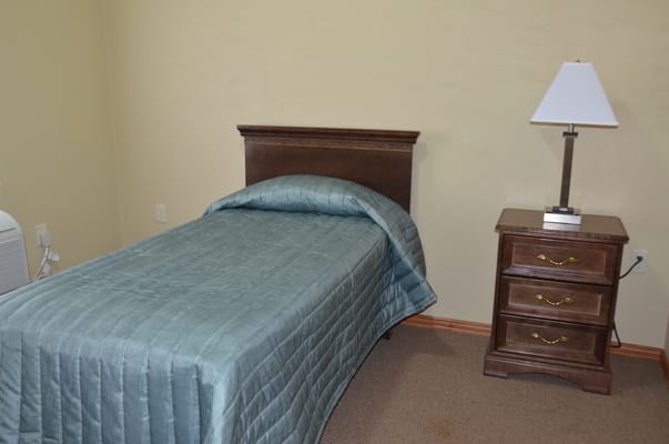 A private resident room with a bed and nightstand
