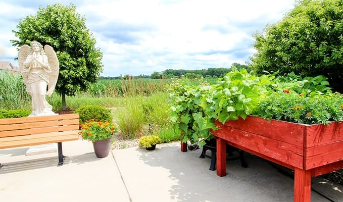 A serene garden area featuring a statue and raised flower beds.