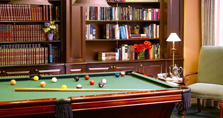 Billiards table in a cozy common area with bookshelves