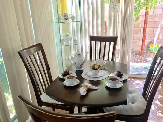 A cozy dining table set with tea, cake, and a small floral arrangement.