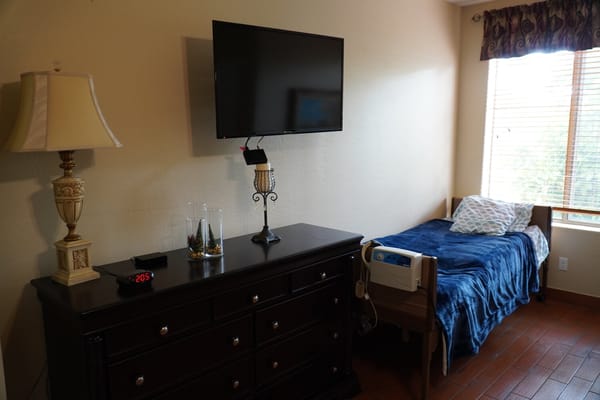 Private resident room with a bed, dresser, and TV