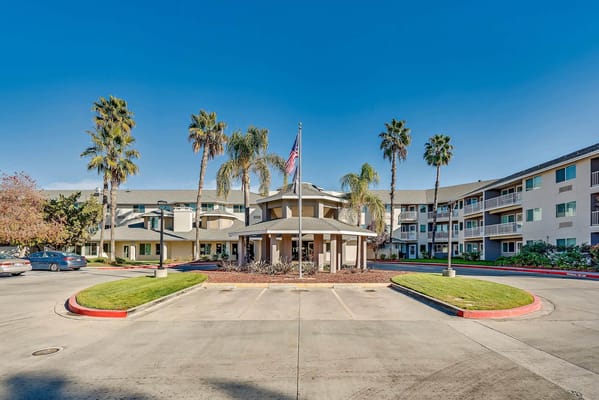 Entrance view of The Remington Senior Living with palm trees.