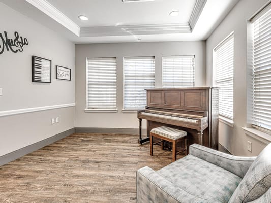 Cozy lounge area featuring a wooden piano and natural light.