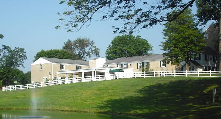 Exterior of Jacob's Well Assisted Living facility with green lawn and white fence.