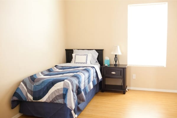 A simple private resident room with a bed and lamp