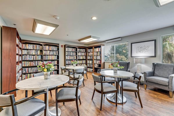 Cozy library with bookshelves and seating at The Remington Senior Living.