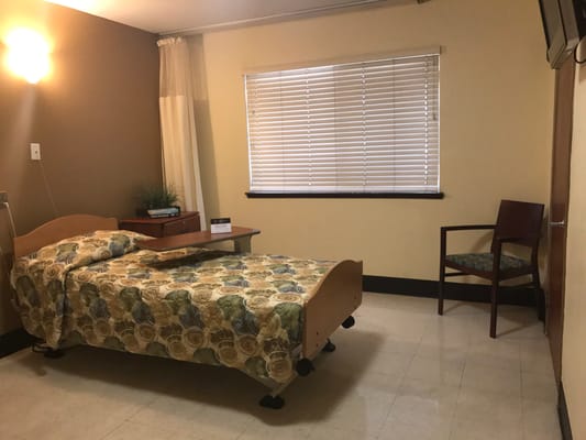 A private resident room with a bed and chair