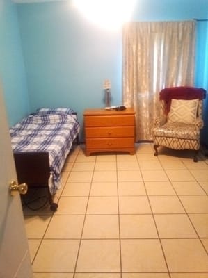 A private resident room with bed and chair