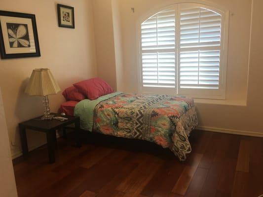 A cozy bedroom featuring a bed with colorful bedding, a bedside table, and a lamp.