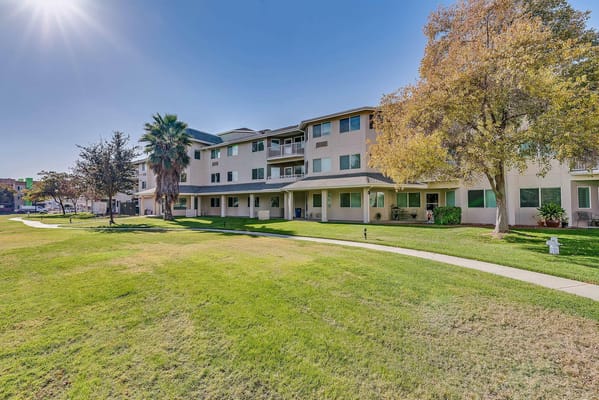 Sunny exterior of The Remington Senior Living with landscaped courtyard