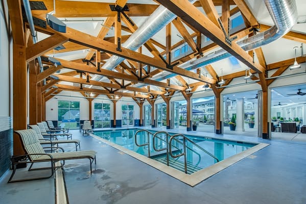Indoor swimming pool surrounded by wooden beams and seating