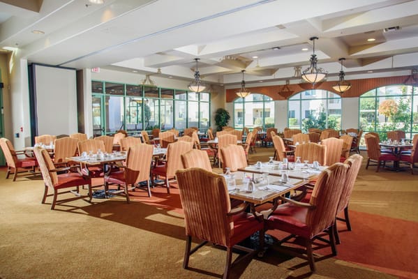 Well-lit dining area with tables and chairs set for meals