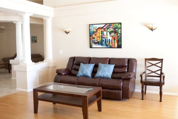 Living room with brown couch, two blue cushions, and a wooden coffee table.