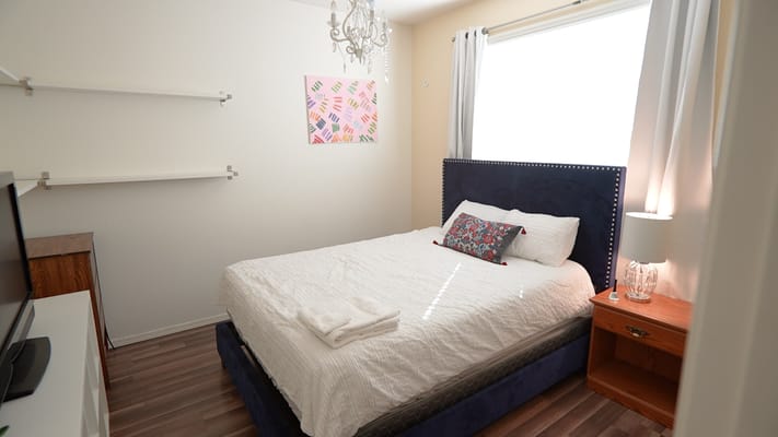 A neatly arranged bedroom with a blue bed, decorative pillow, and a chandelier.
