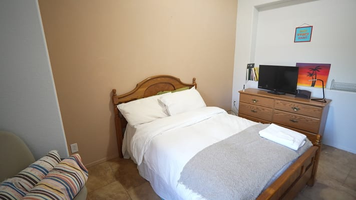 Cozy bedroom with a bed, dresser, and television
