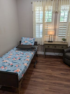 A cozy room with a floral bedspread, bedside lamp, and a small desk.