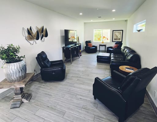 A comfortable living room with black leather furniture and decorative wall art.