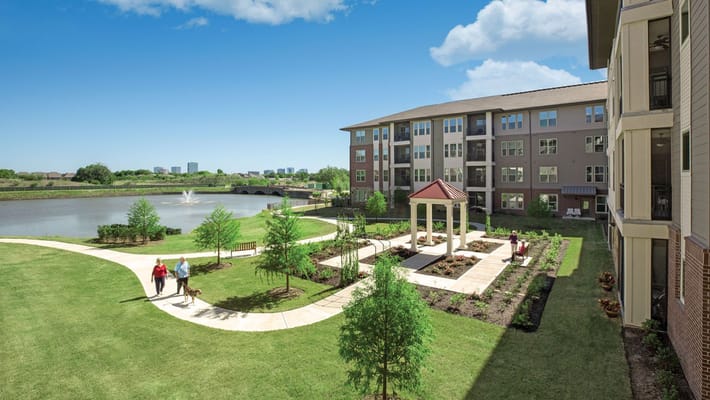 Residents strolling through landscaped outdoor area by the lake