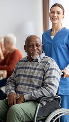A caregiver with a resident in a wheelchair in a facility