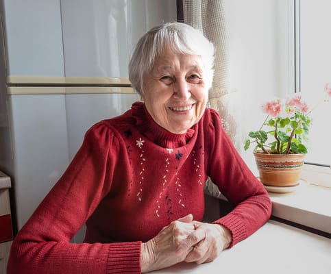 Smiling elderly woman at a table by a window