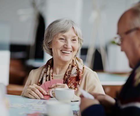 Senior woman enjoying tea and playing cards