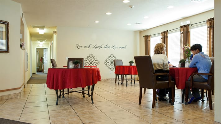 Residents engaged in a common area with tables and decor