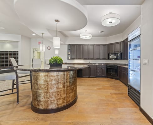 A modern kitchen with a curved counter and dark cabinets.
