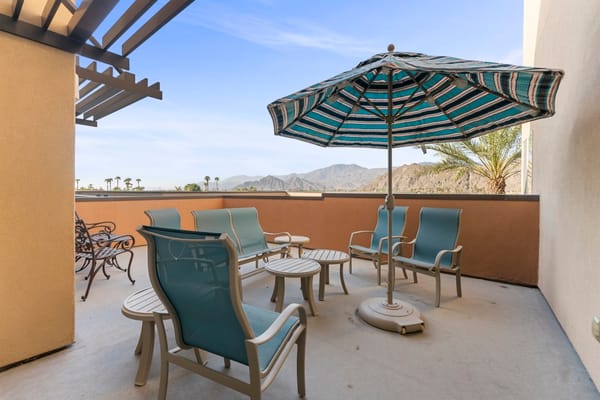 Patio area with chairs and umbrella overlooking mountains