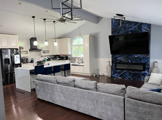 Spacious living room with a modern design, featuring a gray sofa and kitchen area.