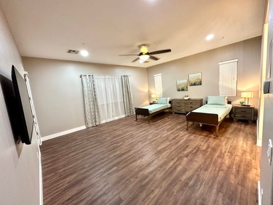 Spacious shared bedroom with two beds, nightstands, and wall art.