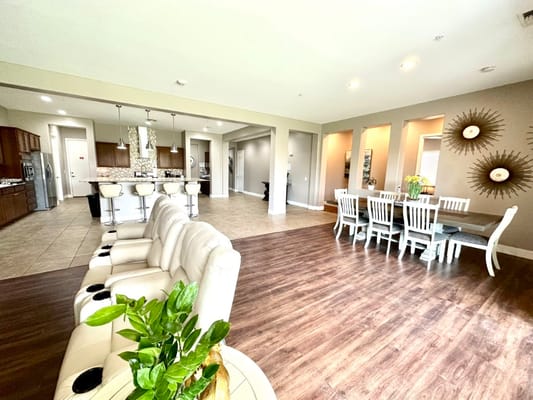 A bright living room with a kitchen in the background, featuring modern furniture and decor.