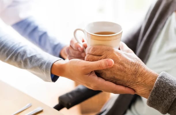 Caregiver handing a cup to a senior resident