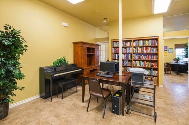 Interior view of a common area with bookshelves and piano