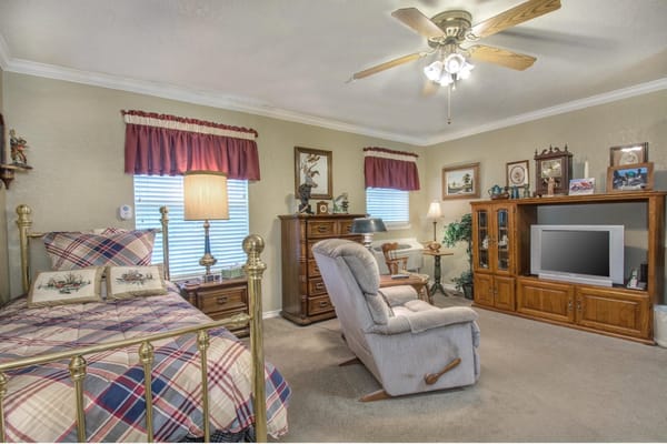Stylish bedroom with a gold bed frame, recliner, and wood furnishings.
