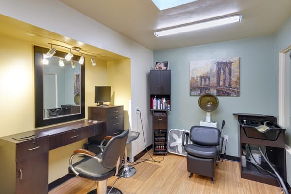 Beauty salon area with styling chairs and mirror