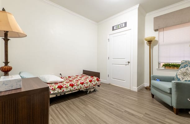 A cozy resident room with a bed and chair