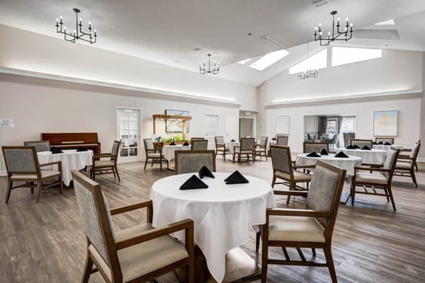 Dining area with tables set for meals at Crescent Landing memory care facility.